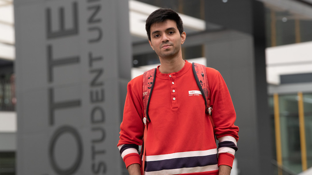 A photo of a CSUMB student in front of the Otter Student Union building