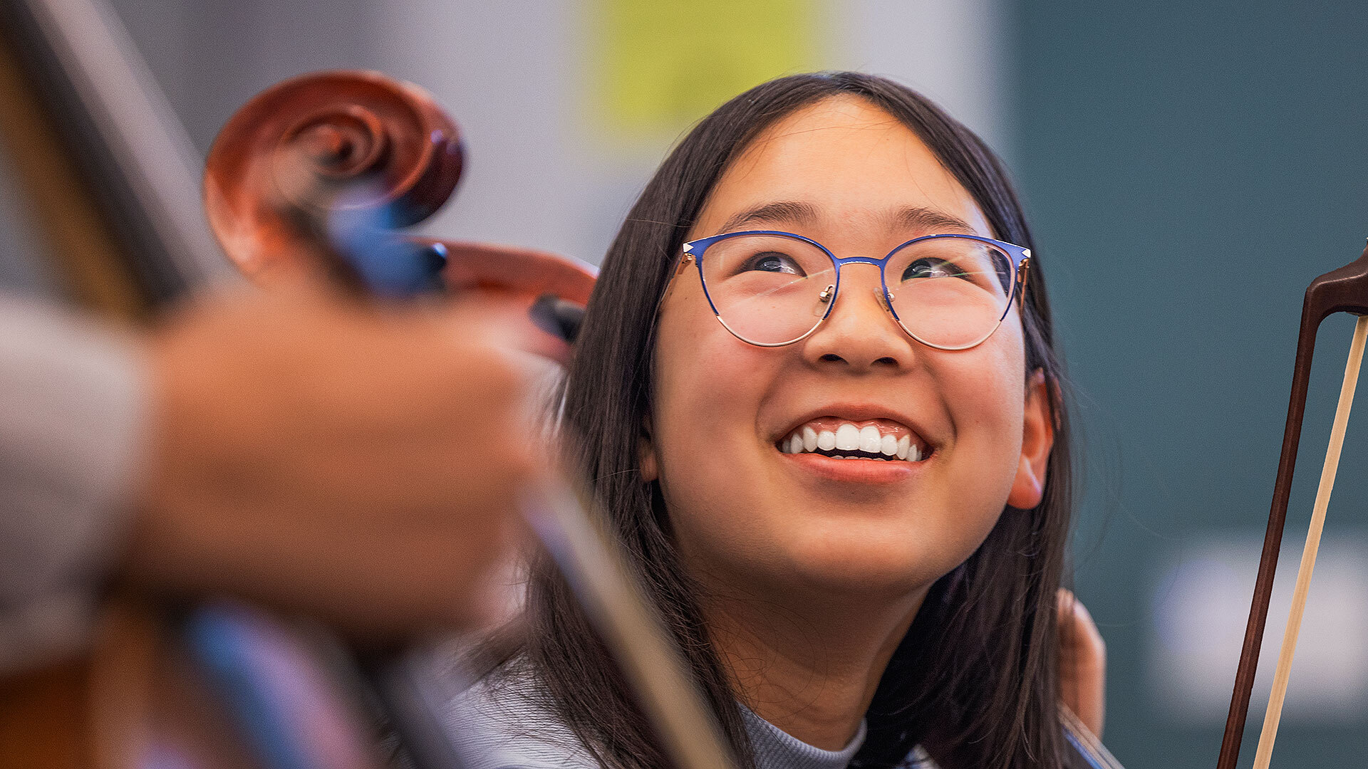 Female student with glasses smiling while holding a Cello