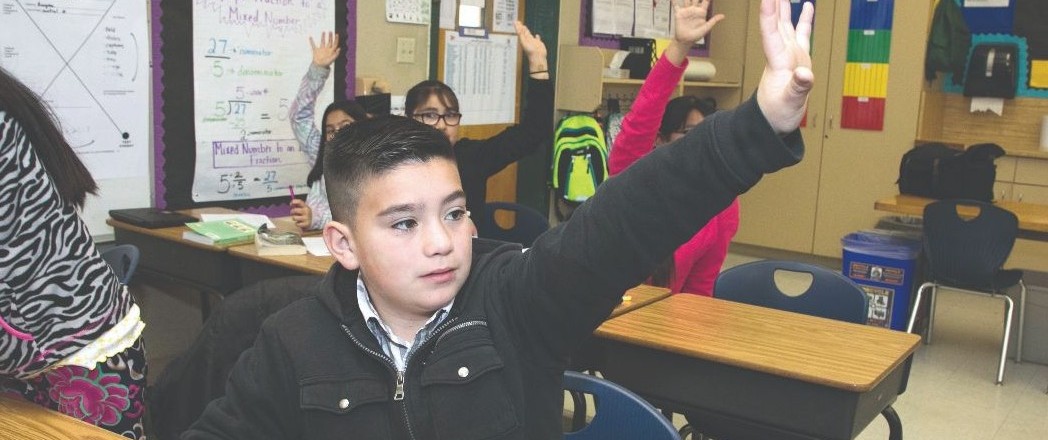 student at desk raising hand