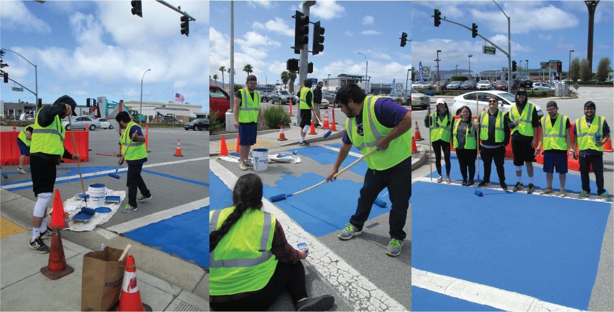 Students wearing yellow safety vests painting a crosswalk in Seaside.