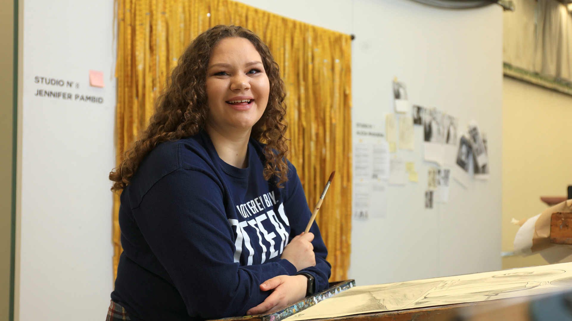 CSUMB student holding a paintbrush