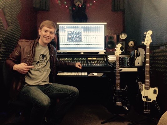 Drew Lassen at mixing board with guitars in background