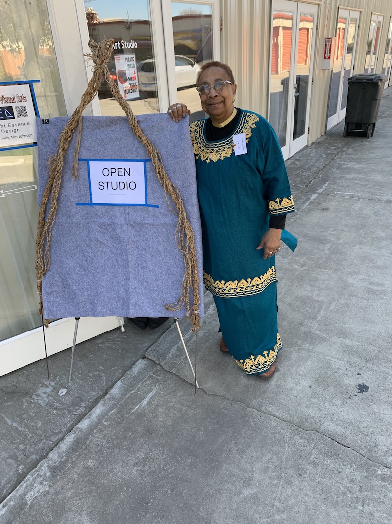 Stephanie Johnson pictured outside with a sign for Open Studio