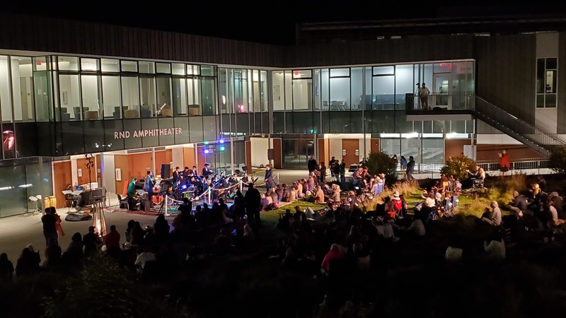 students, faculty and community members sitting outdoors enjoying a performance by Monterey Jazz Festival musicians