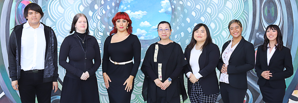 Students and instructor posed in front of Skylight: Transmission of Knowledge/Windows to Justice mural