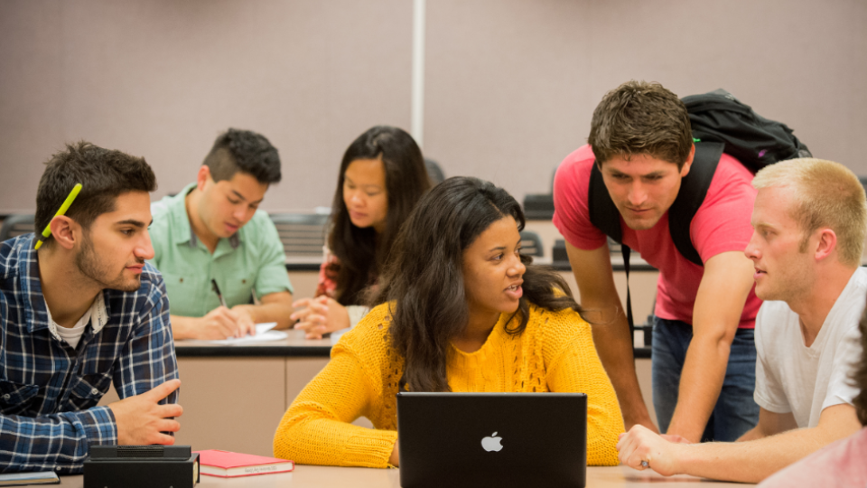 Students looking at laptop and talking