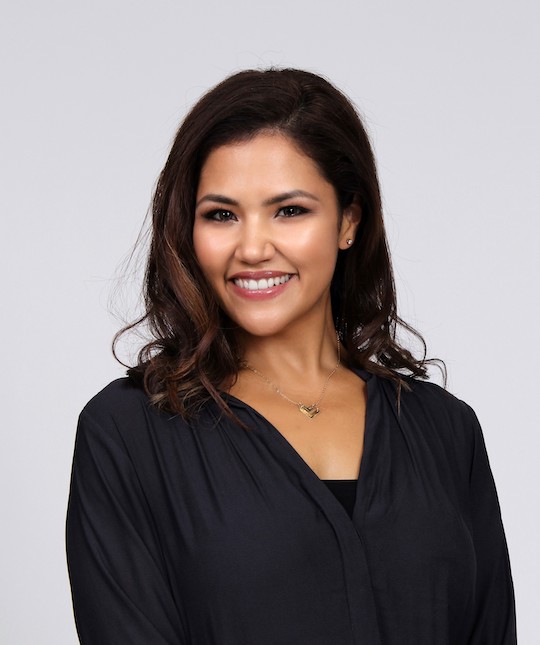 A dark haired woman smiling in a black long sleeved shirt