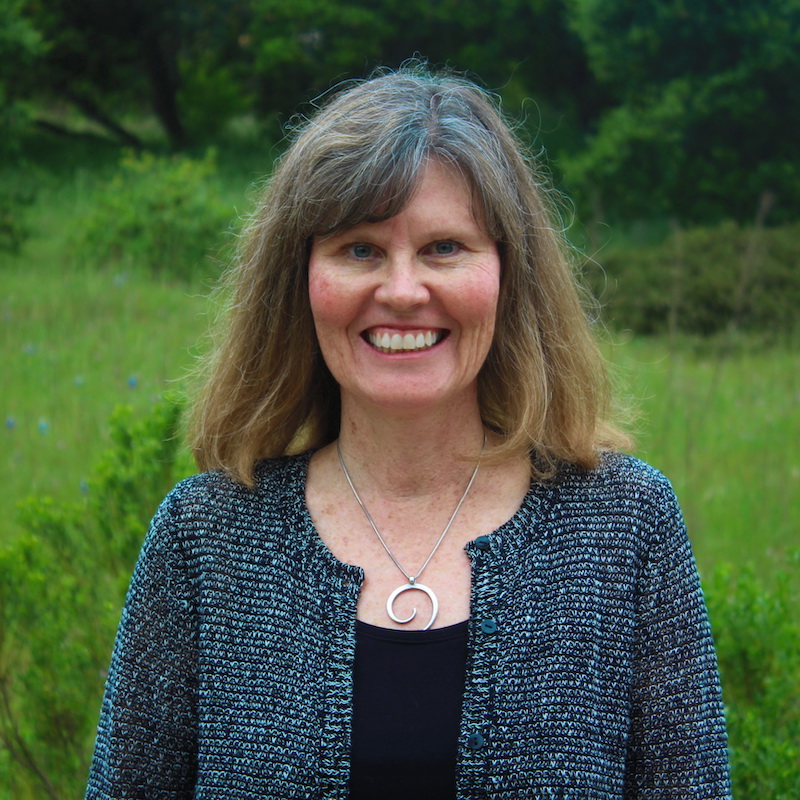 A picture of Dr. Susan Alexander standing in front of a grassy field