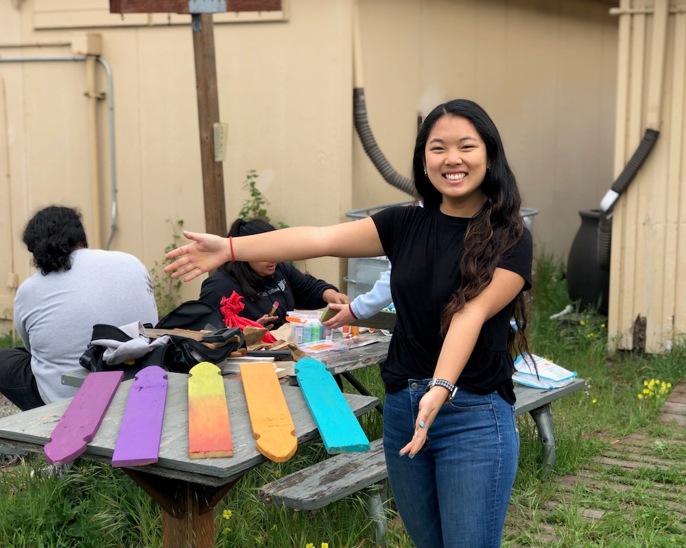 Environmental studies student shows off their painted fence posts