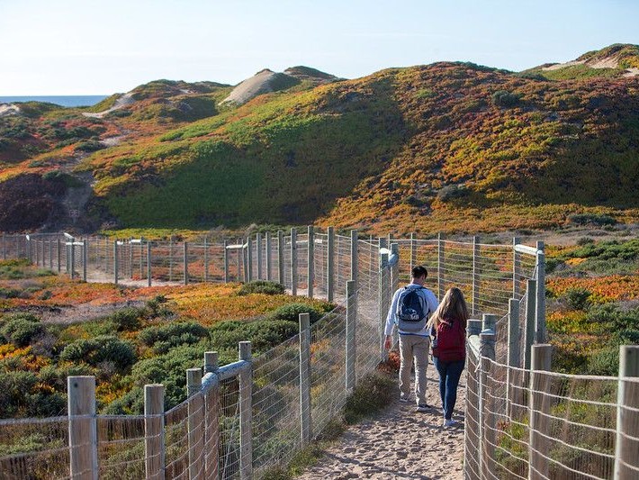 Photo of two csumb students walking down a path to the beach