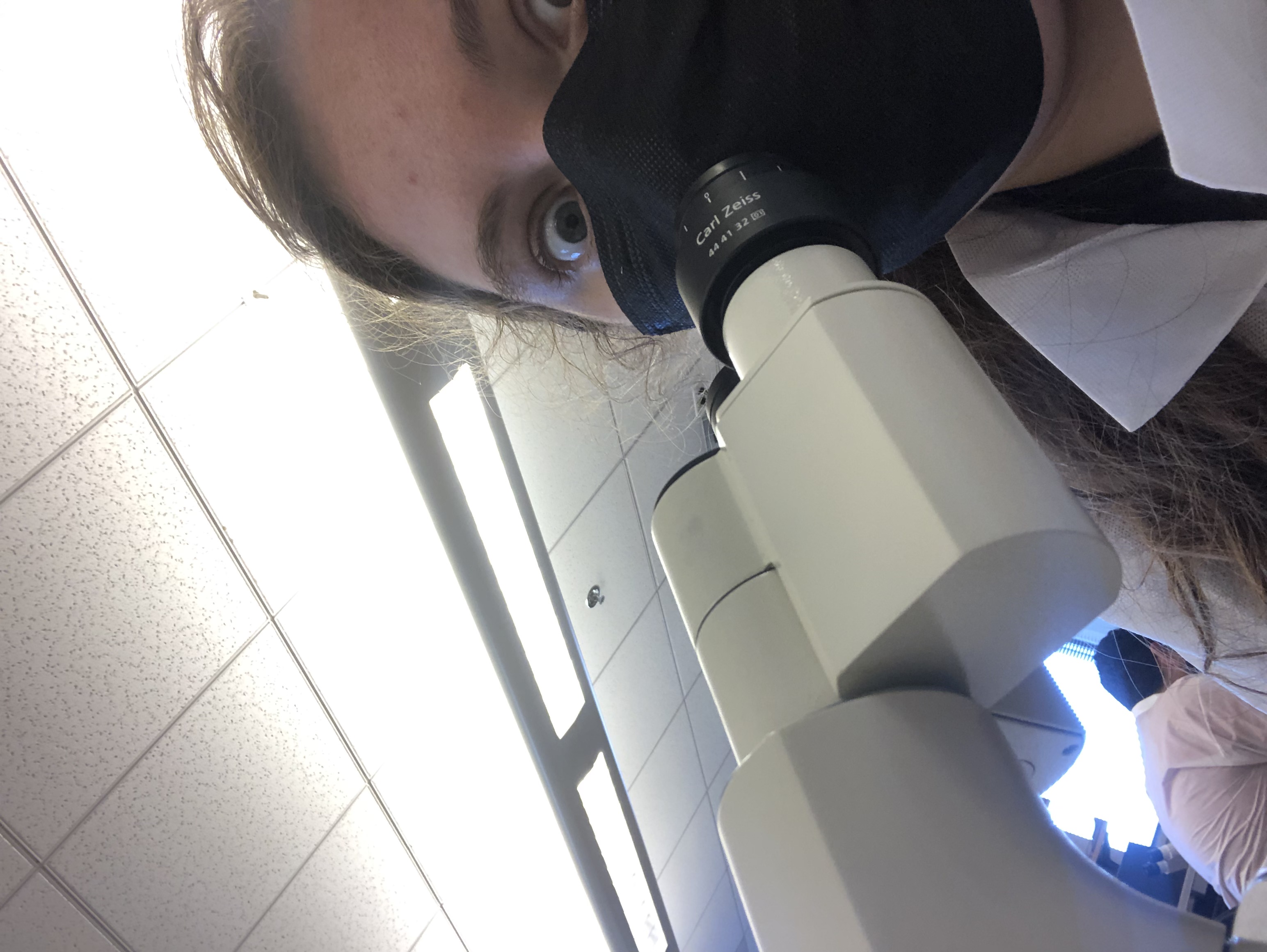 Juliana looking into the camera, a microscope in front of her.