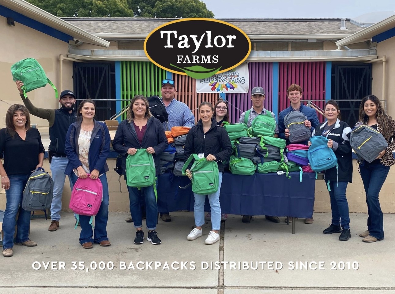 Jesus and other workers standing and smiling for the camera. Each person holds a backpack.