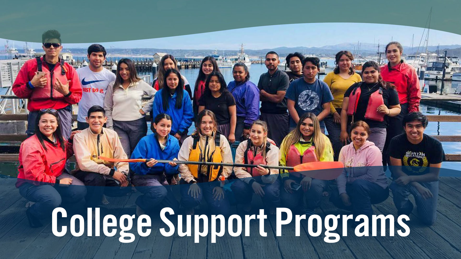 Image of students in front of water and the wharf holding an ore