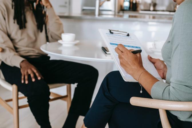 Interviewer writing notes on clipboard