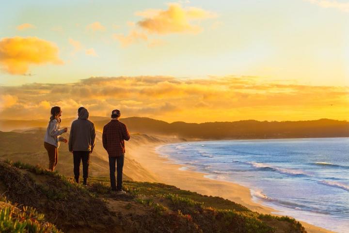 Three students at the beach overlooking the sunset