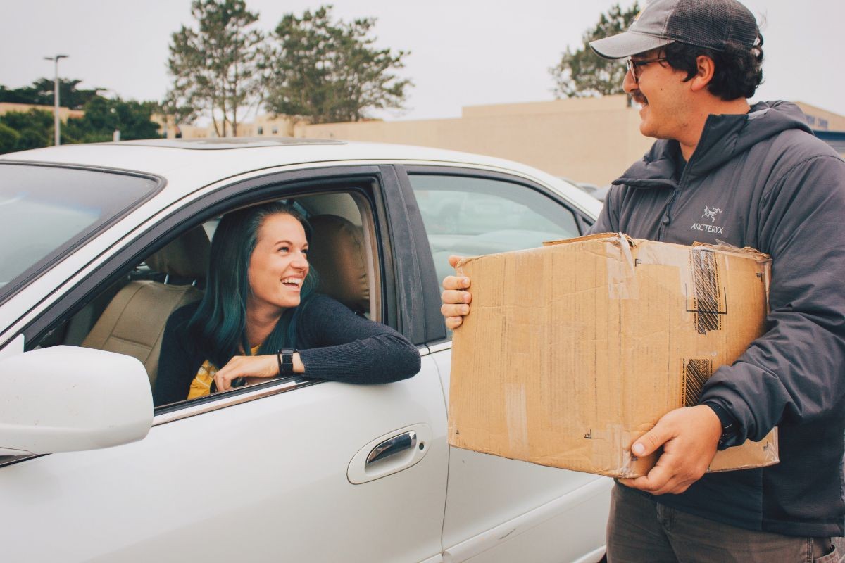 Two students moving in, one in her car, one standing with a box