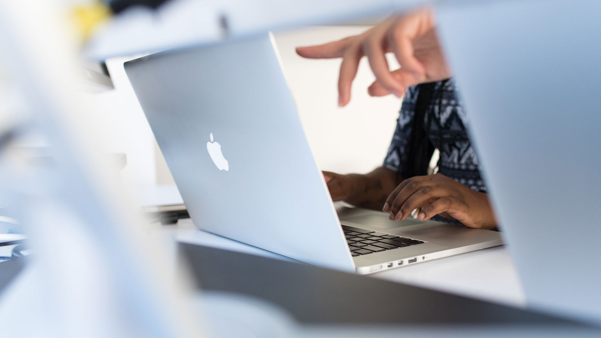 Photo: Women pointing at and using a Mac laptop