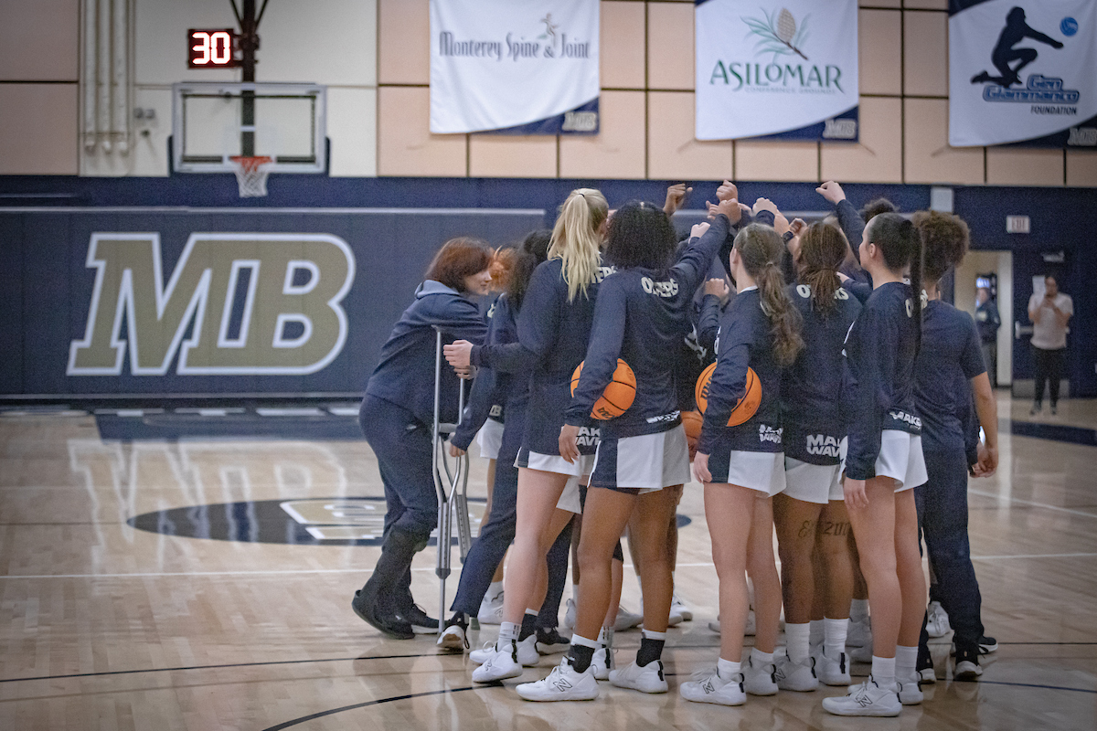 Women's basketball athletes huddling