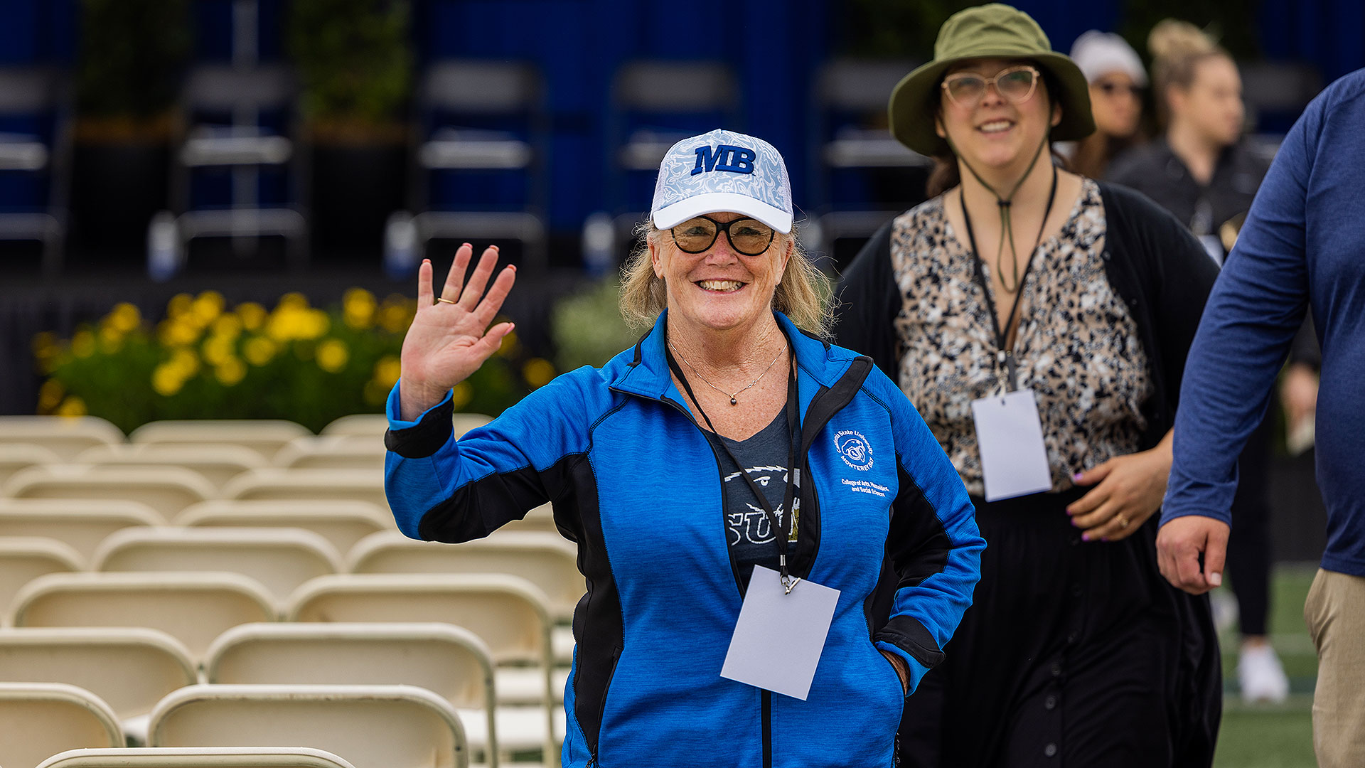 Staff member waving at the camera during Commencement