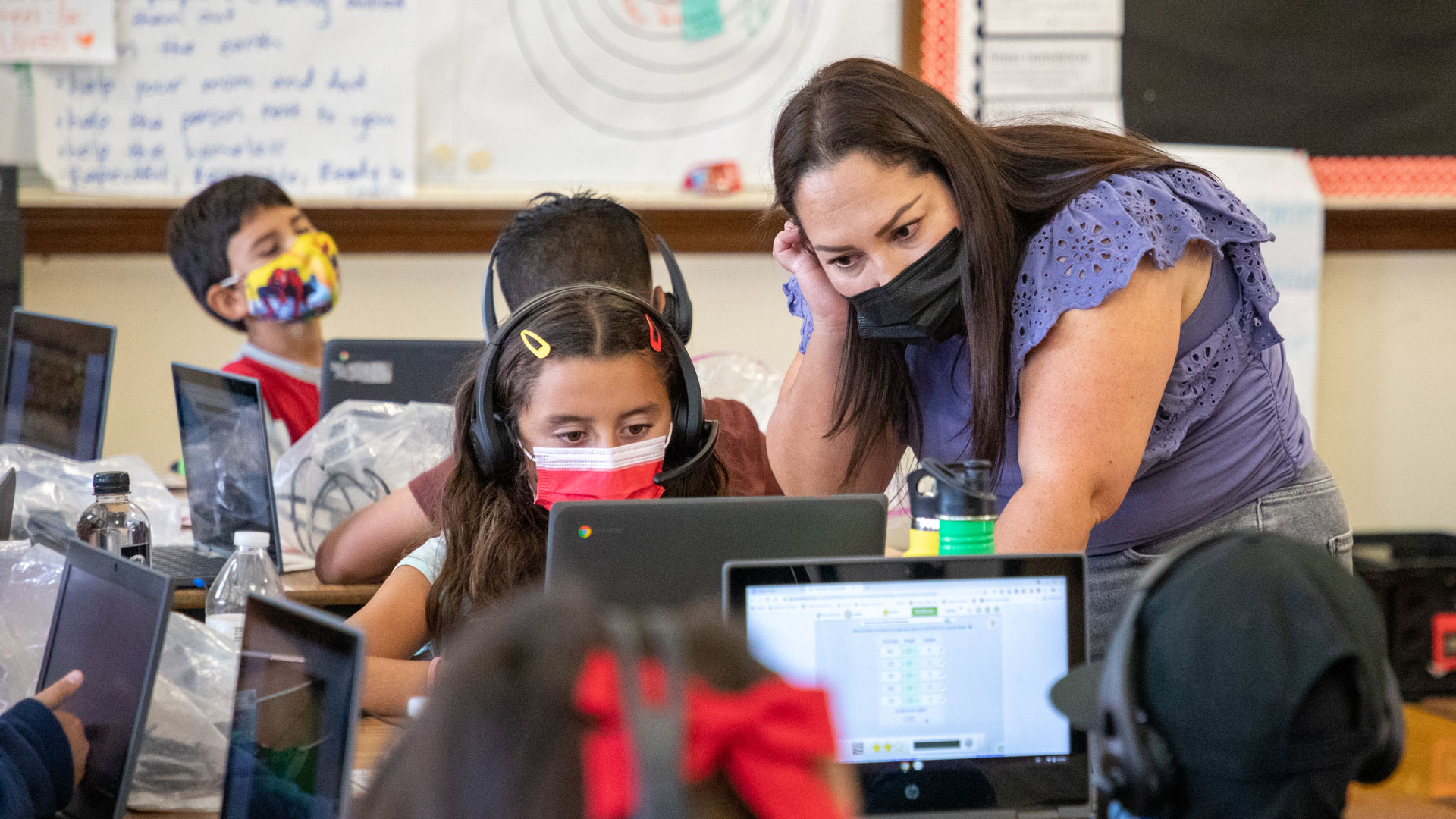 Photo: CSUMB student and co-teacher Gabriela Suarez answers a student’s question during a math lesson.